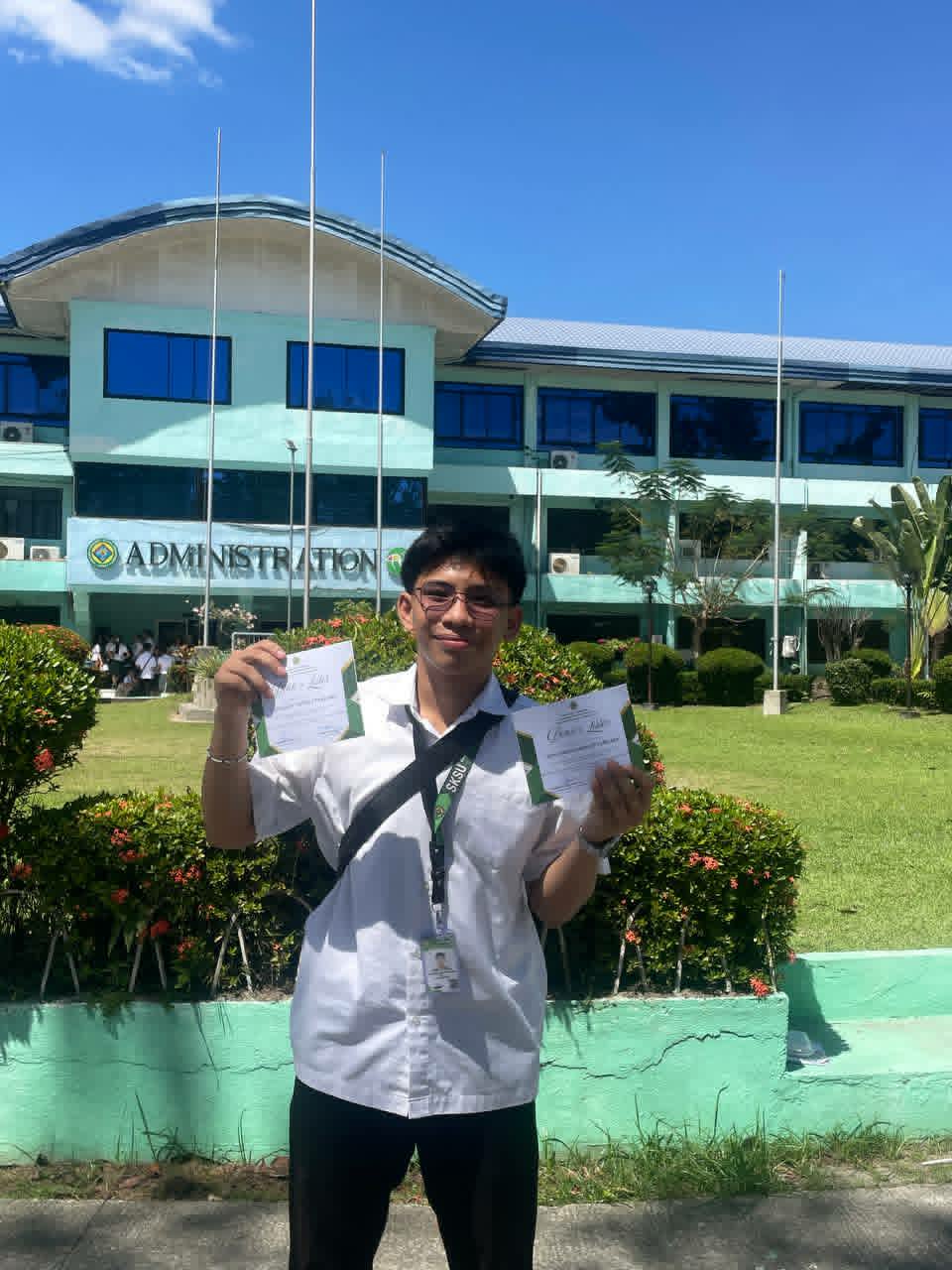 Von holding two academic certificates outside the university administration building